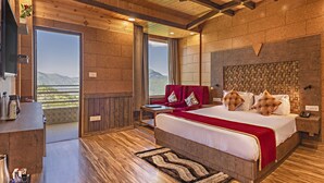 A spacious bedroom with a large bed, wooden floors, a view of the mountains, and a balcony. - Kanishka Retreat Resort Chail (Kandaghat)