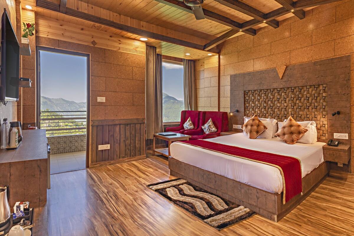 Une chambre spacieuse avec un grand lit, un plancher en bois, une vue sur les montagnes et un balcon.