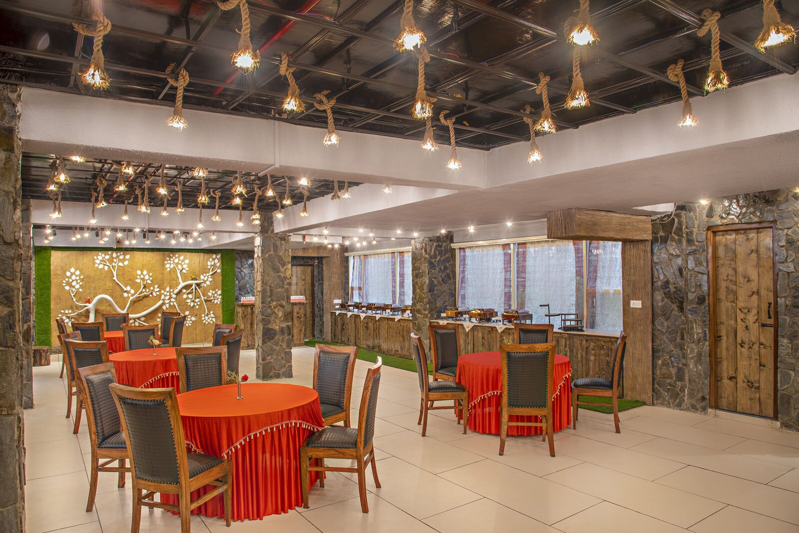 Restaurante com mesas redondas, cadeiras e luzes de corda penduradas.