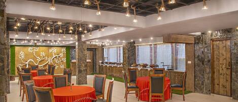 A restaurant with round tables, chairs, and hanging rope lights.