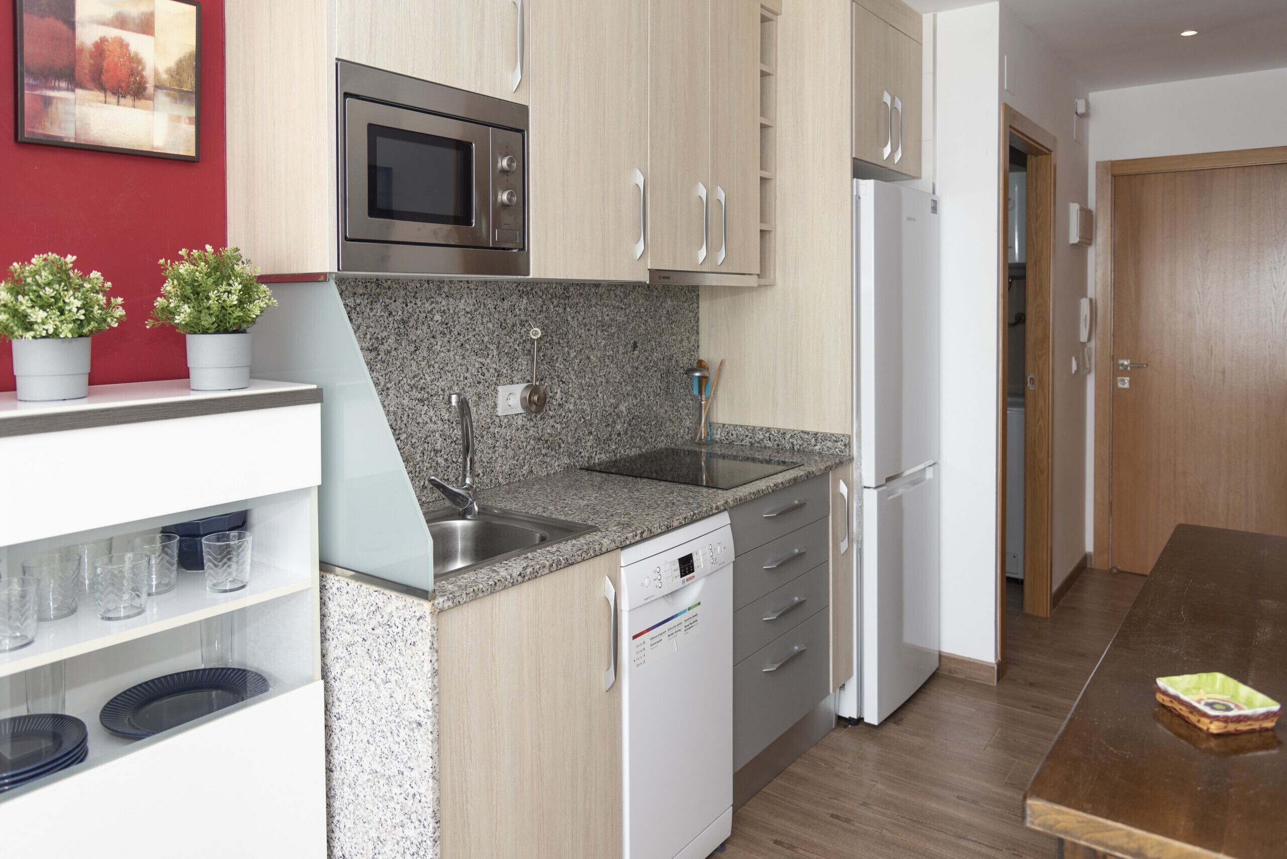 Une cuisine moderne dotée de plans de travail en granit, d’appareils électroménagers en acier inoxydable et d’armoires en bois.