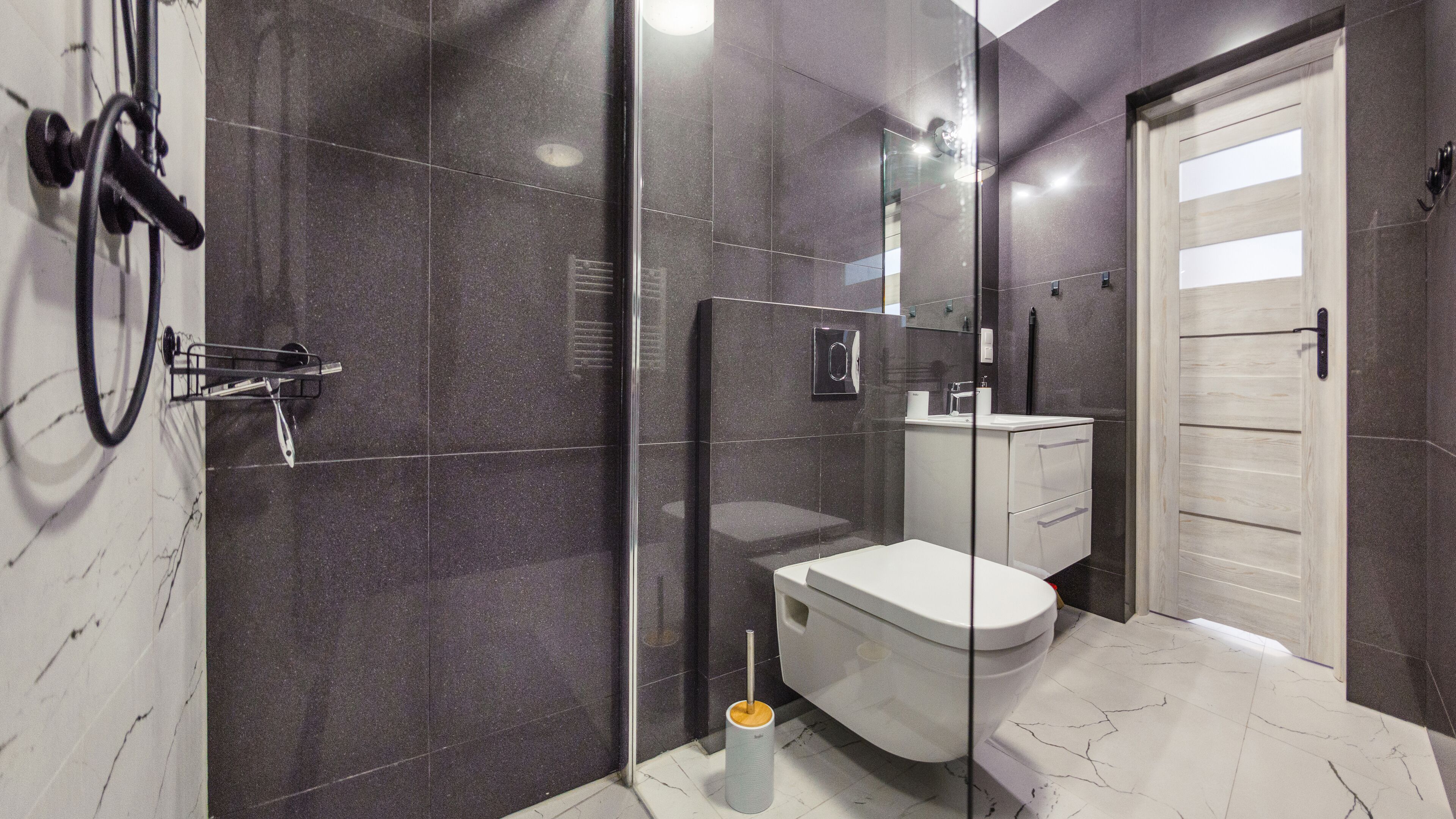 A modern bathroom with a glass shower enclosure, a white toilet, and a marble-tiled floor.