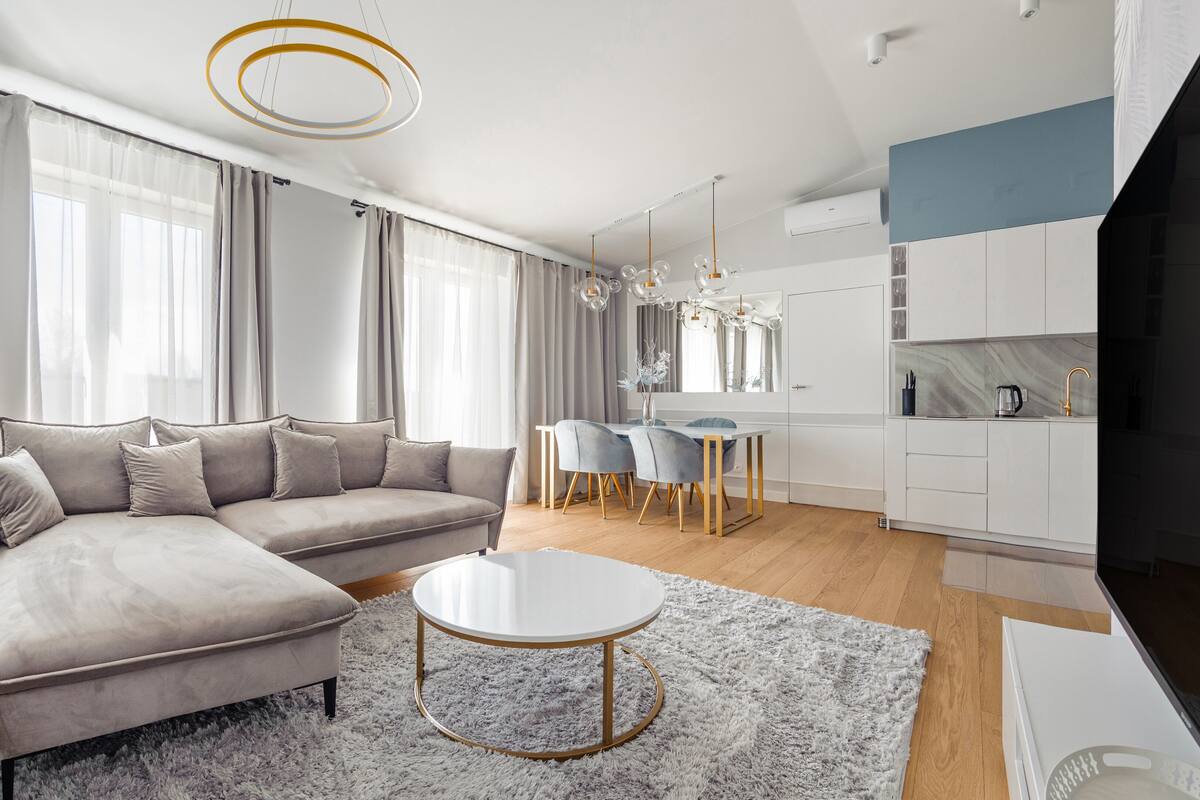 A modern living room with a sectional sofa, a round coffee table, and a dining area with a white table and chairs.