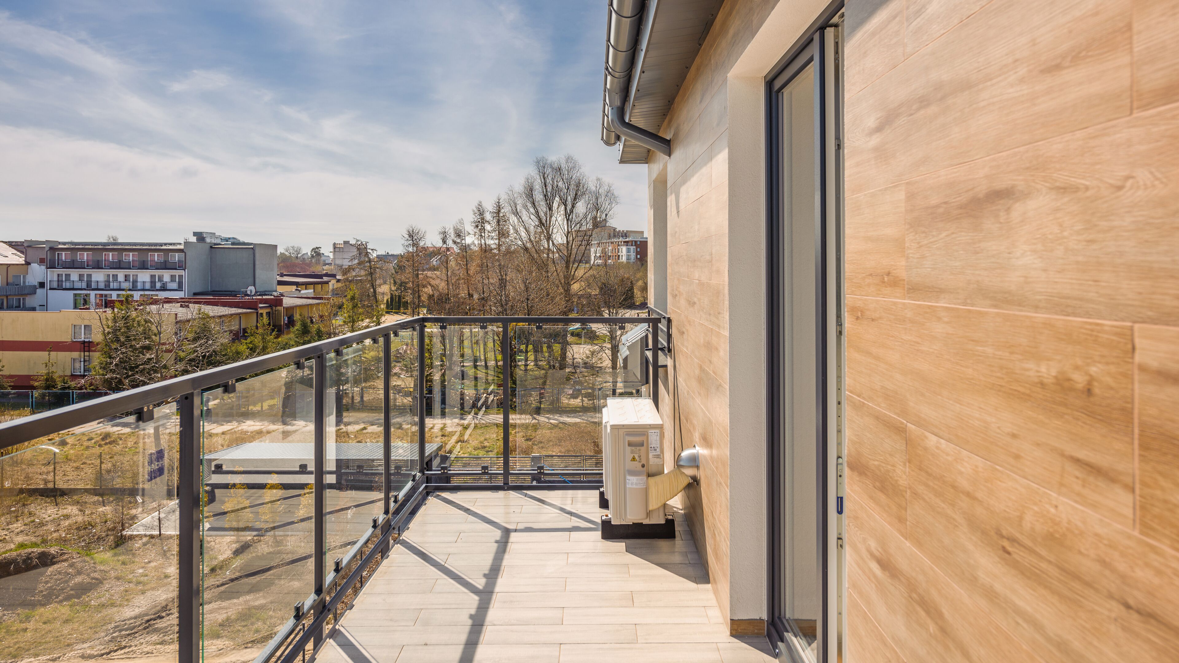 A modern building with a wooden exterior and a balcony with a glass railing.