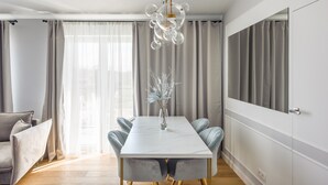 Un espace repas moderne avec une table en marbre, des chaises à revêtement gris et un vase décoratif.