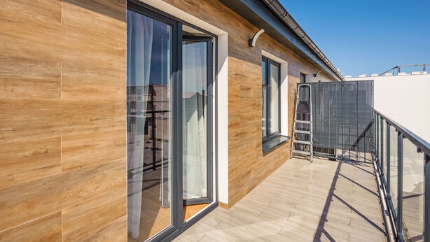 Un bâtiment moderne doté de grandes portes et fenêtres en verre, d’une façade en bois et d’une échelle en métal.