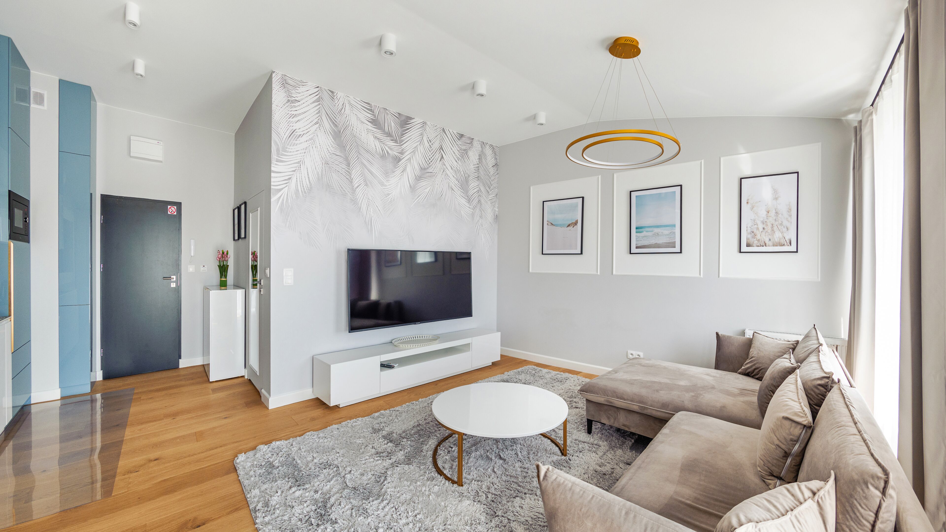 Ein modernes Wohnzimmer mit Flachbildfernseher, einer Couch, einem Couchtisch und Kunstwerken an den Wänden.