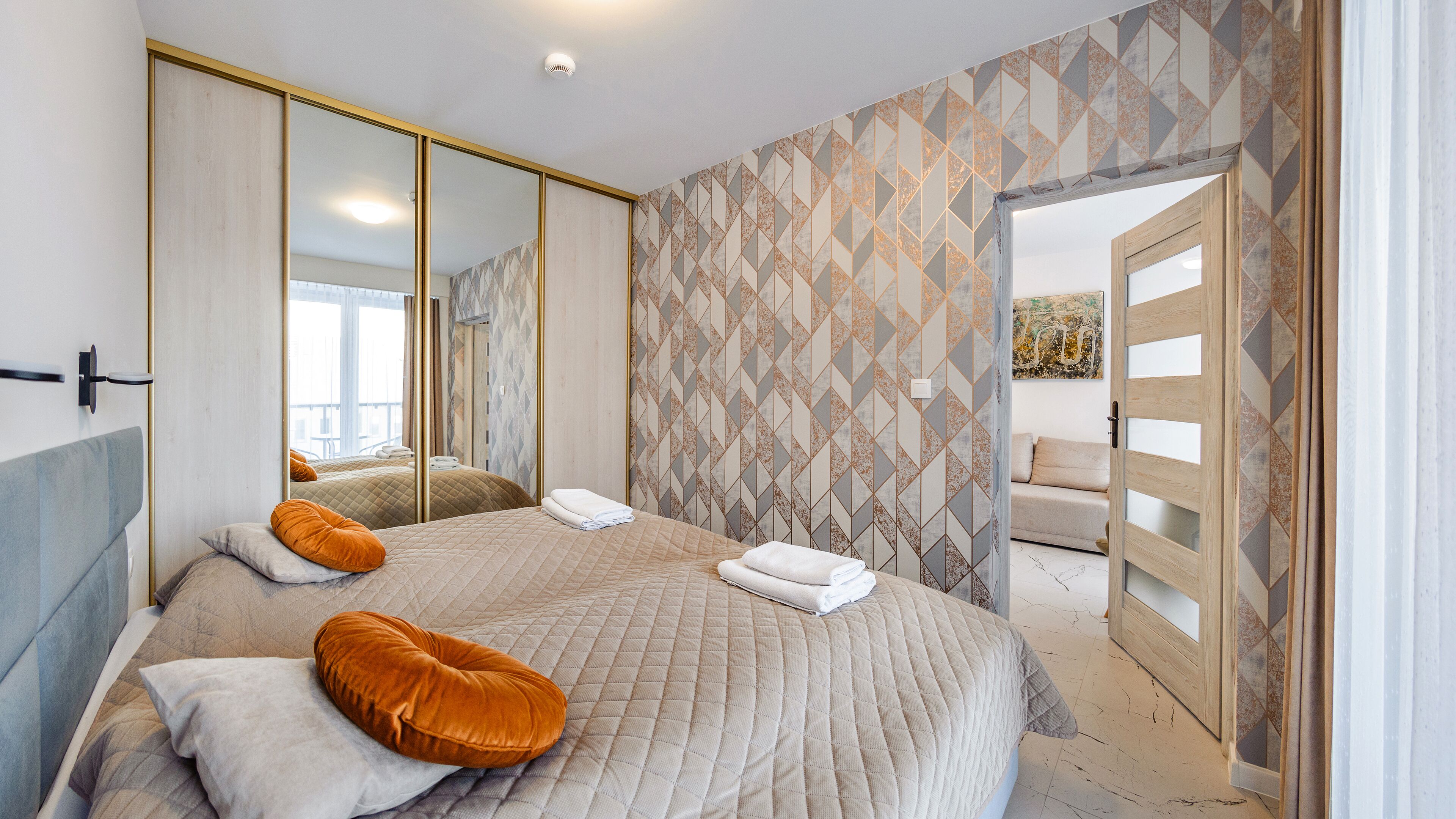 A bedroom with a large bed, a wardrobe, and a mirror.