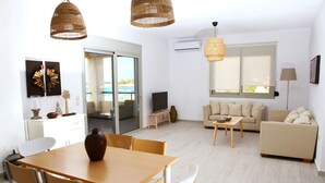 Una sala moderna con comedor, un conjunto de sofás y un televisor.