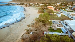 Una zona costera con playa, algunos árboles y una fila de edificios con balcones.