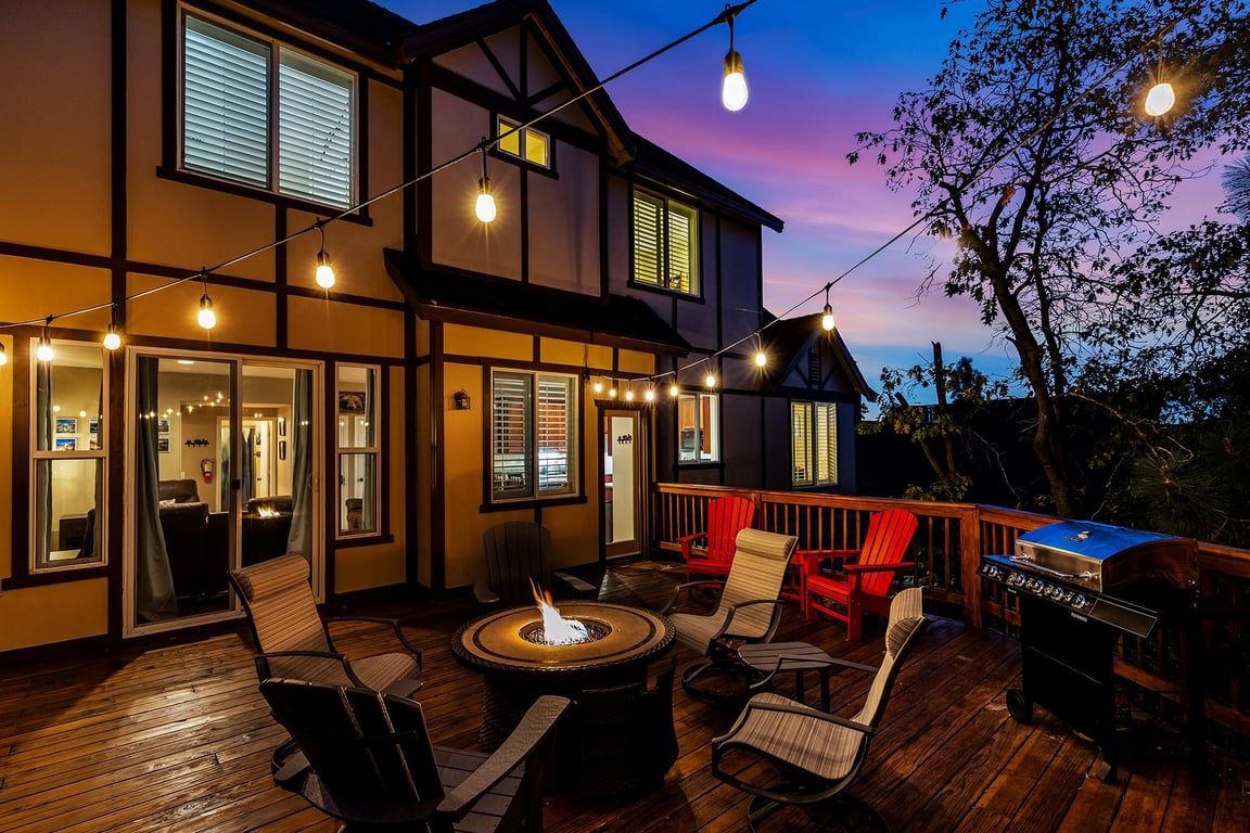 A deck with outdoor seating, a grill, and string lights.