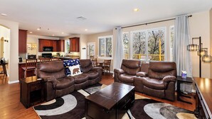 Ein geräumiges Wohnzimmer mit Ledersofas, einem Couchtisch und einem Essbereich mit Holztischen und -stühlen.