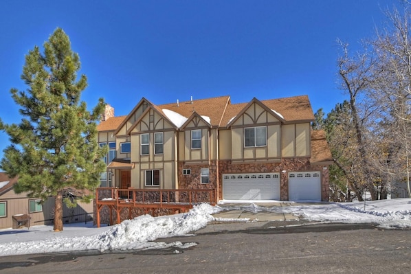 A two-story house with a stone facade, a wooden deck, and a garage.