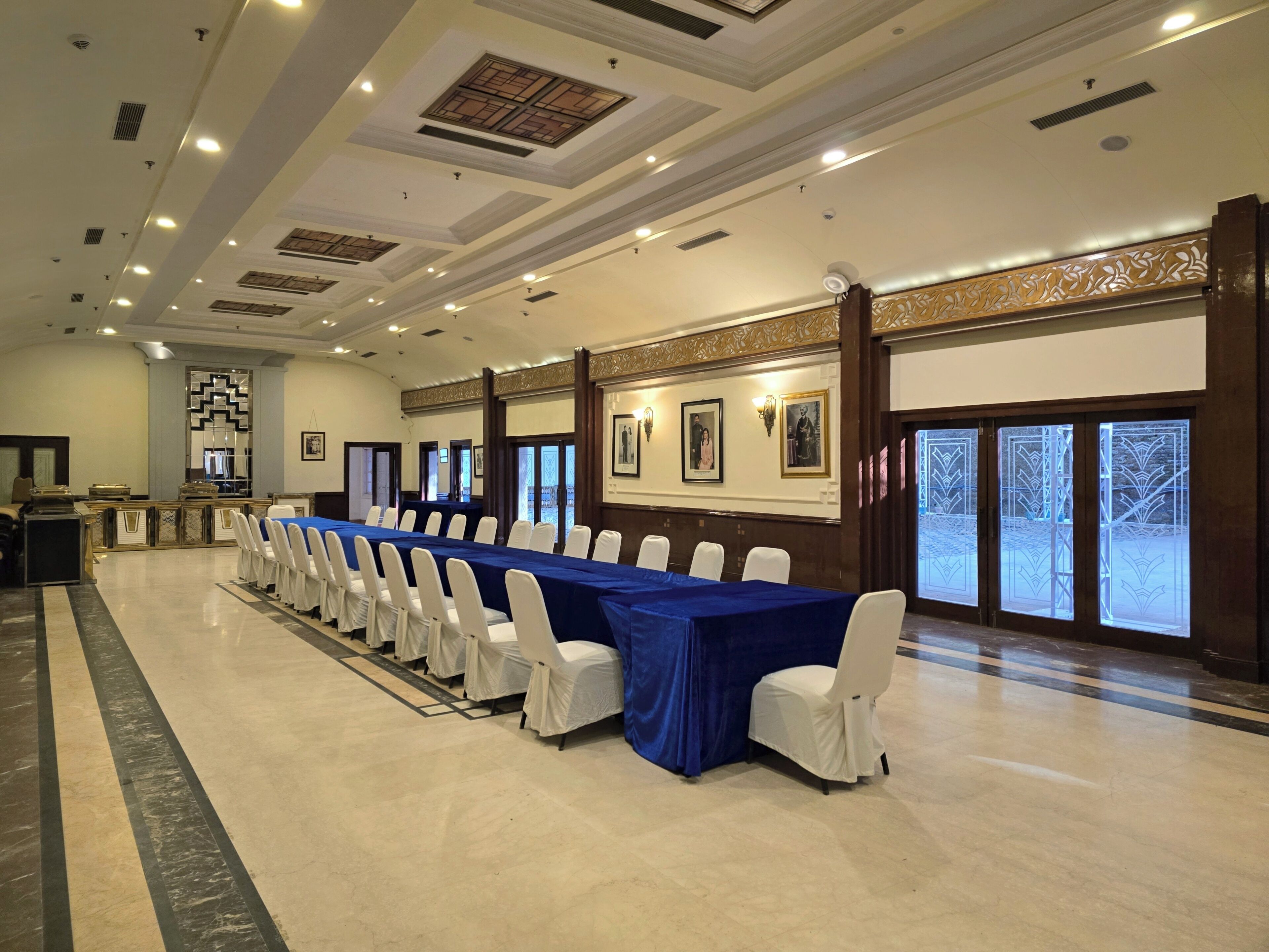 A conference room with a long table, white chairs, and a blue tablecloth.