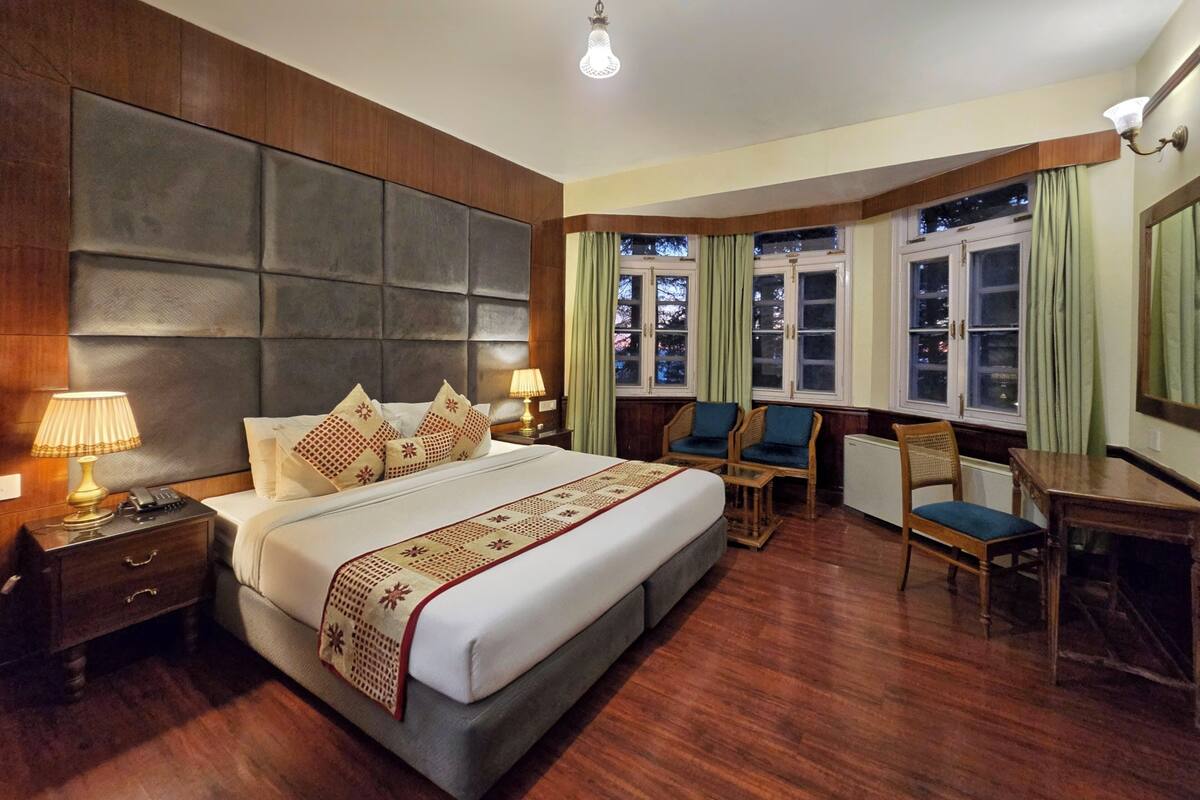 Ein Hotelzimmer mit einem großen Bett, zwei Nachttischen, einem Schreibtisch und einem Sessel.