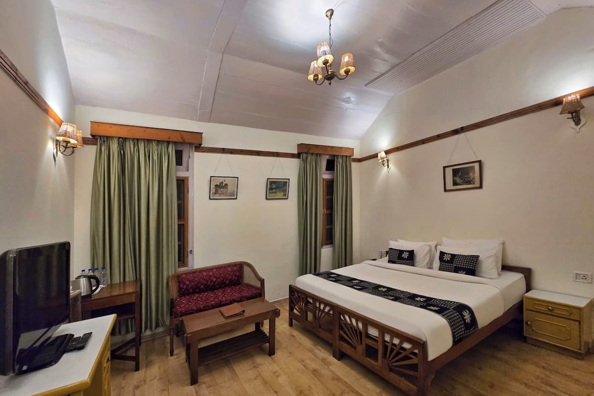 Ein Hotelzimmer mit Bett, Sofa, Schreibtisch und Fernseher sowie einer Kandelaber.