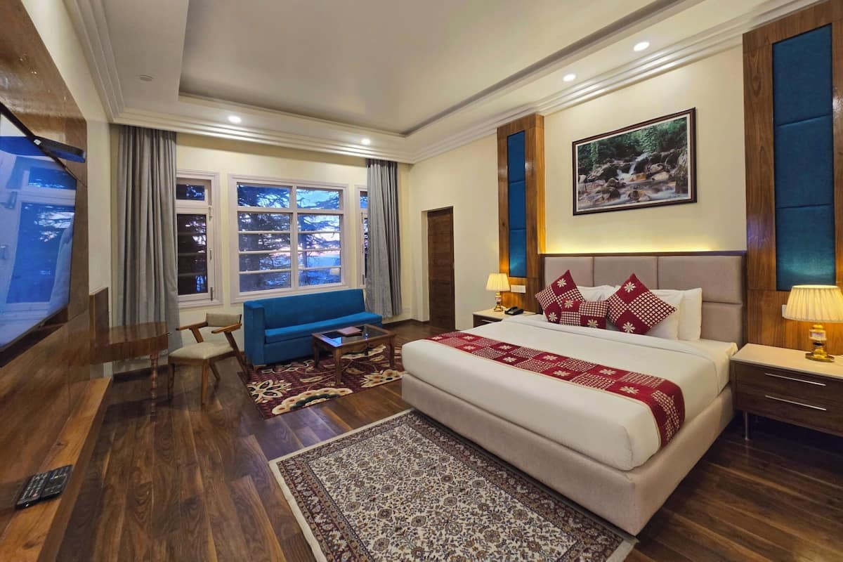 Ein Hotelzimmer mit einem großen Bett, einem blauen Sofa, einem Fernseher und einem Fenster mit Vorhängen.