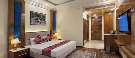 A modern hotel room with a large bed, bedside tables, a TV, and a wooden wardrobe.
