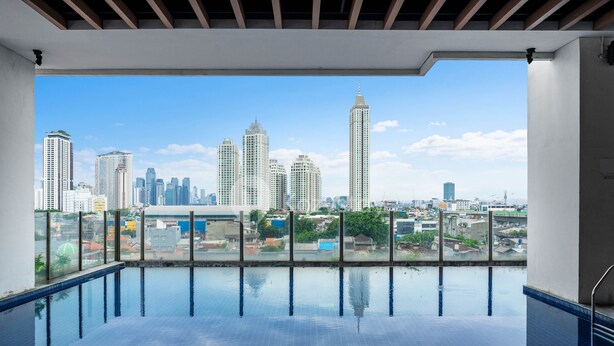 An indoor swimming pool with a cityscape view. - AKASA by Kozystay (Jakarta)