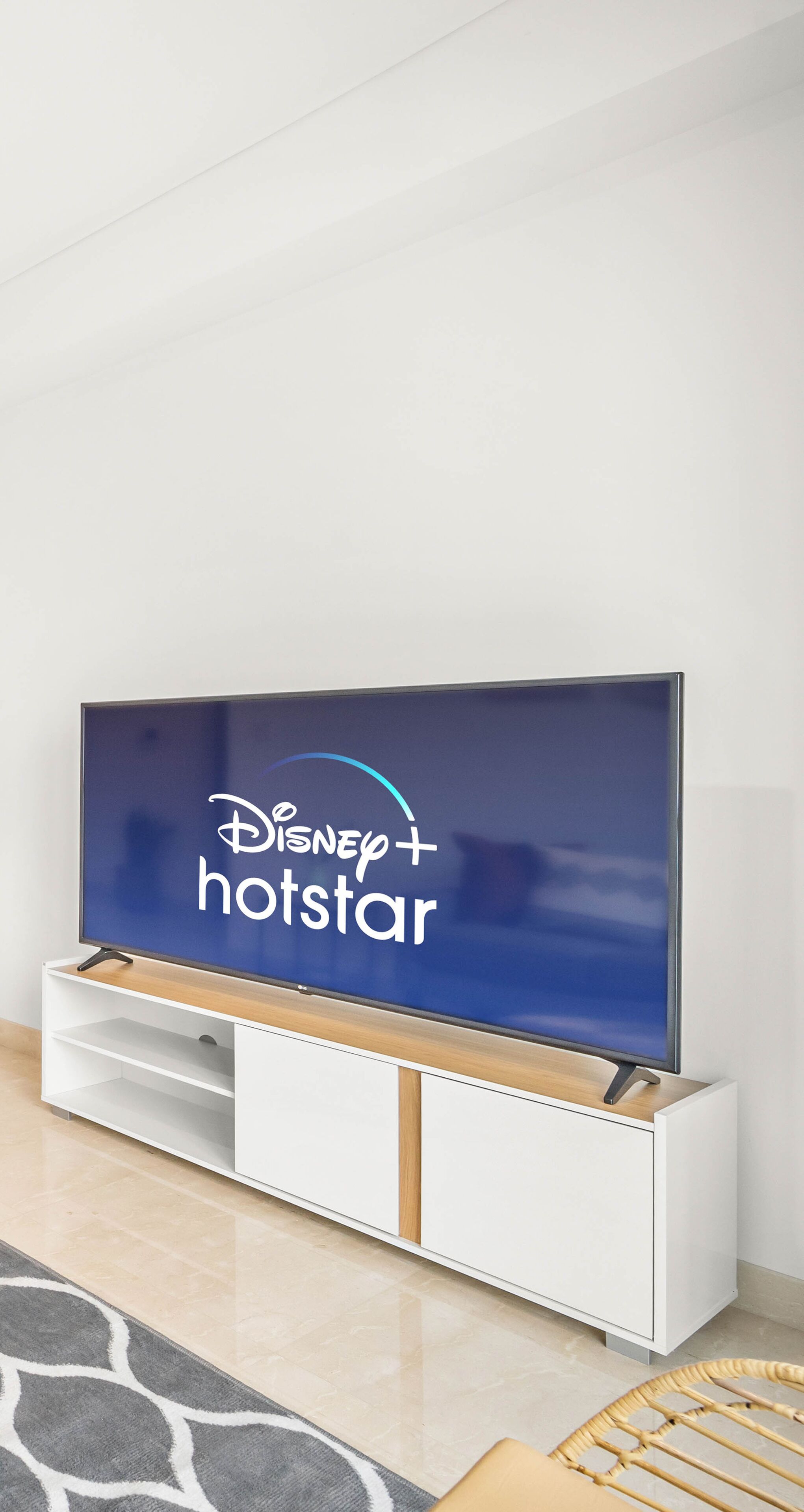 A flat-screen TV on a white entertainment unit with a Disney+ hotstar logo.