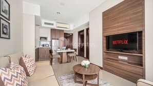 Una sala de estar moderna con un sofá, una mesa redonda de centro y un televisor de pantalla plana montado en una pared de madera.