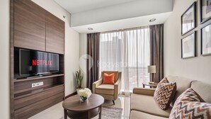 Una sala moderna con televisor de pantalla plana, un sofá, un sillón, una mesa de centro y una planta en maceta.
