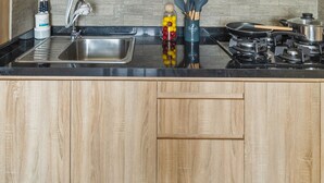 Een keuken met een inbouwvaatwasser, een spoelbak, een fornuis en houten keukenkastjes.