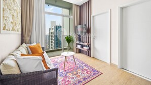 Een moderne woonkamer met een bank, een kamerkleed, een bijzettafeltje en een televisie op een dressoir.