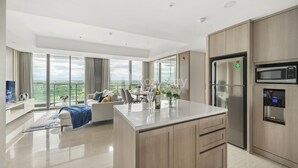 A modern kitchen with a central island, stainless steel appliances, and a dining area with a view. - VUE by Kozystay (Curug)