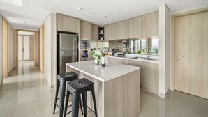 A modern kitchen with a central island, stainless steel appliances, and wooden cabinetry. - VUE by Kozystay (Curug)