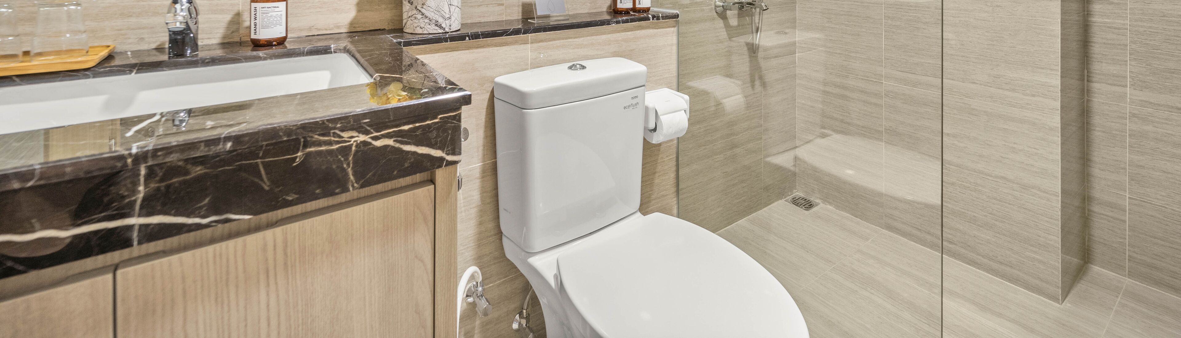 Ein modernes Badezimmer mit einem мраморный Waschbecken, Toilette und Duschbereich.