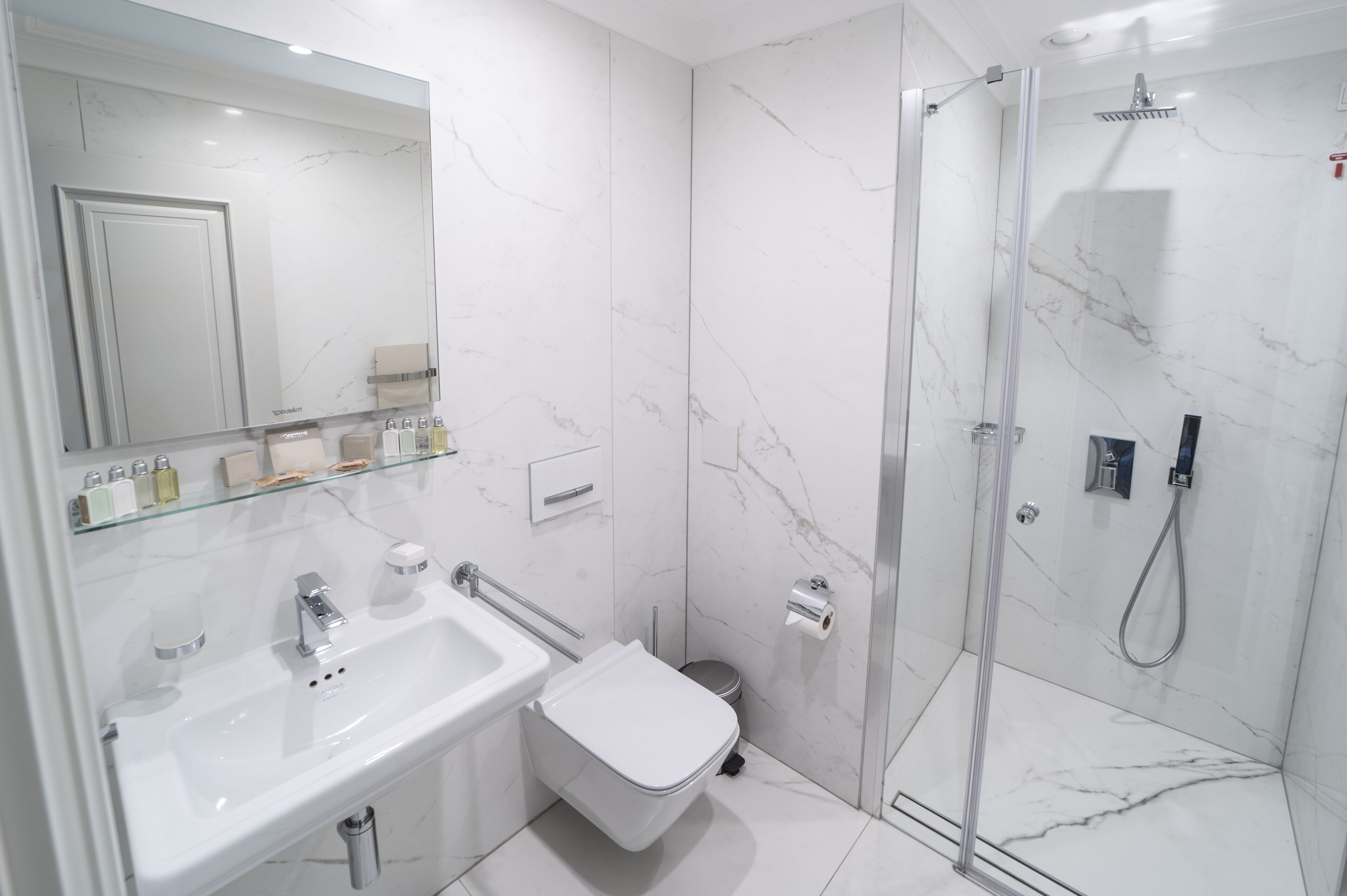 A modern bathroom with a glass shower enclosure, a white sink, and a toilet.