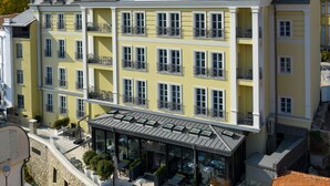 Un hotel de varios pisos con balcones, una terraza en la azotea y un diseño arquitectónico moderno.