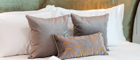 A bed with white and gray pillows, a green headboard, and a patterned bedspread.