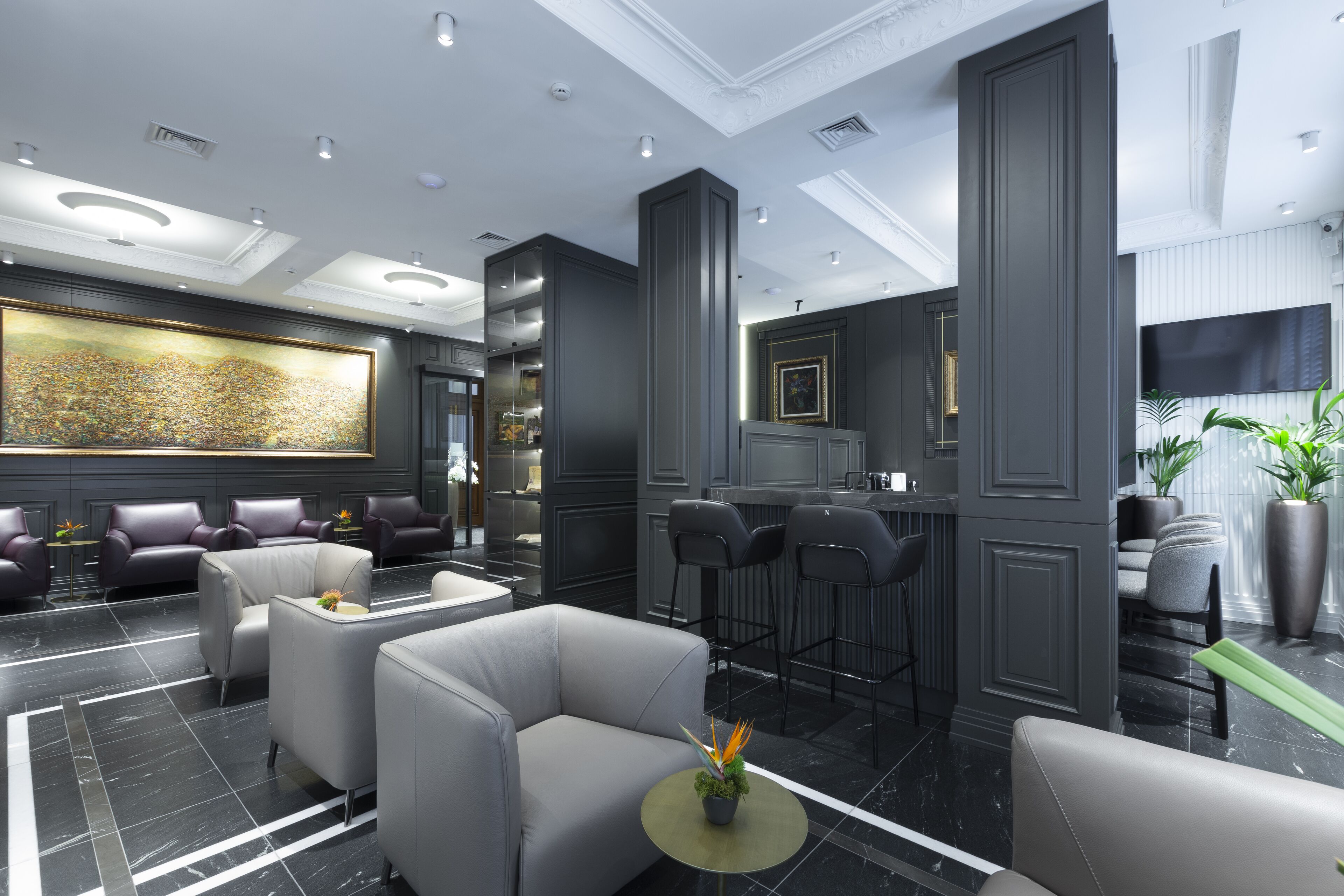 A modern lobby with leather seating, a large abstract painting, and a bar area.