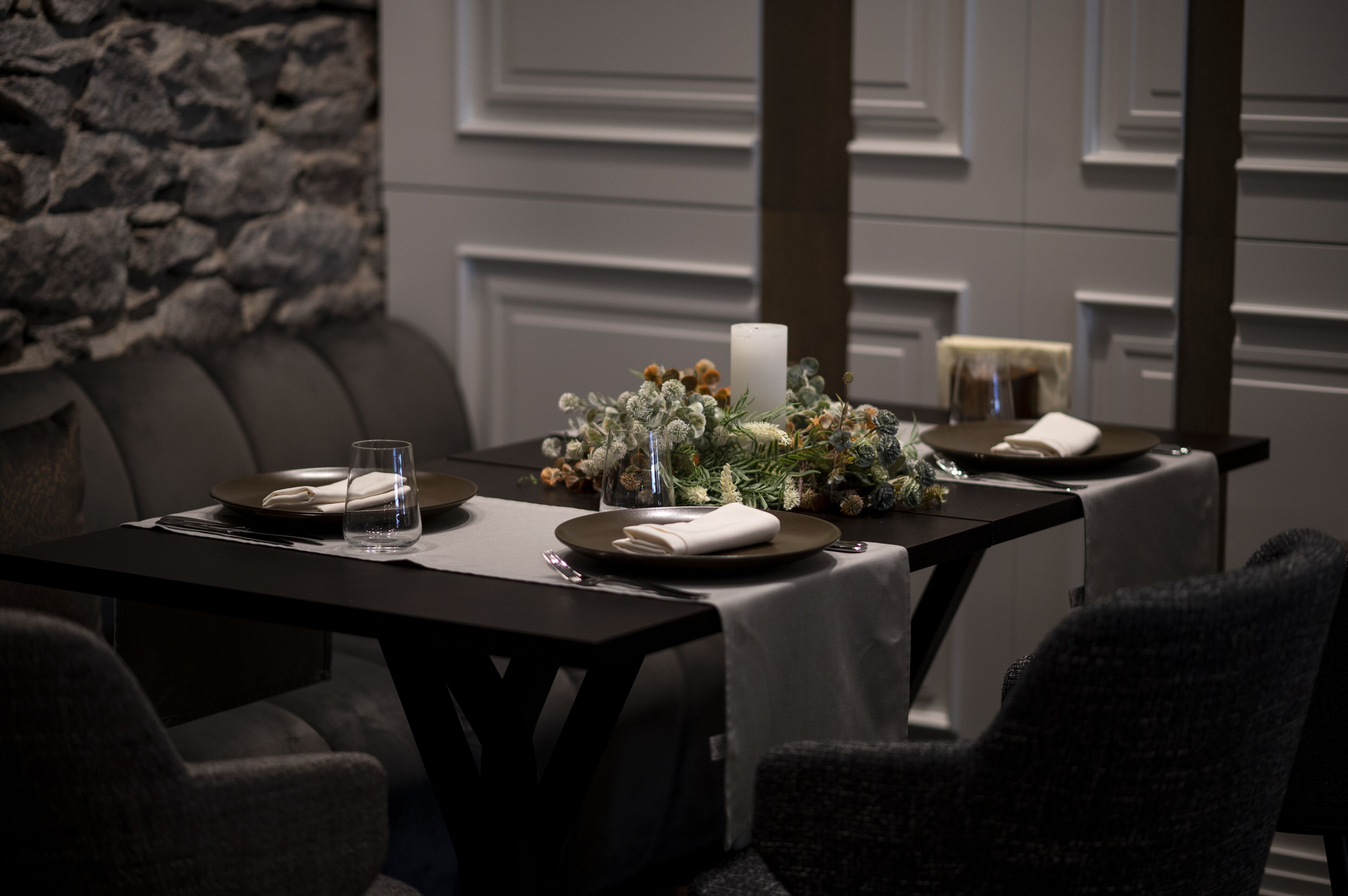 Une table à manger dressée avec des assiettes, des couverts, un verre et un centre de table.