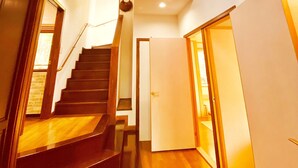 A staircase leading to a second floor with a chandelier and a wall-mounted decoration. - IPPUKAKU (Tsumagoi)