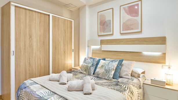 Ein Schlafzimmer mit Bett, Nachttisch, Kleiderschrank und zwei gerahmten Bildern an der Wand.
