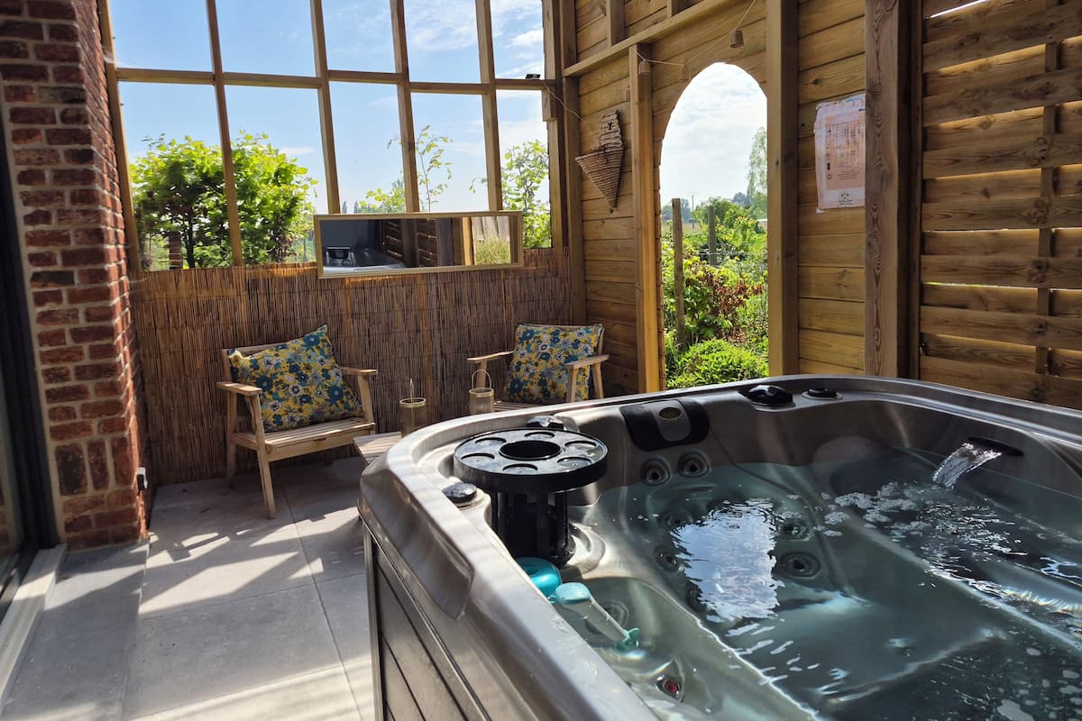 A hot tub in a wooden room with a view of greenery outside.