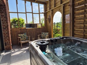 Un bain à remous dans une pièce en bois, avec vue sur la verdure environnante.