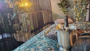 A room with a patterned tablecloth, a metal bucket with a plant, and a decorative wall. - Suites Spa Détente de la lys (La Gorgue)