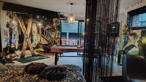 A modern bedroom with a large bed, a dining area, and a staircase. - Suites Spa Détente de la lys (La Gorgue)