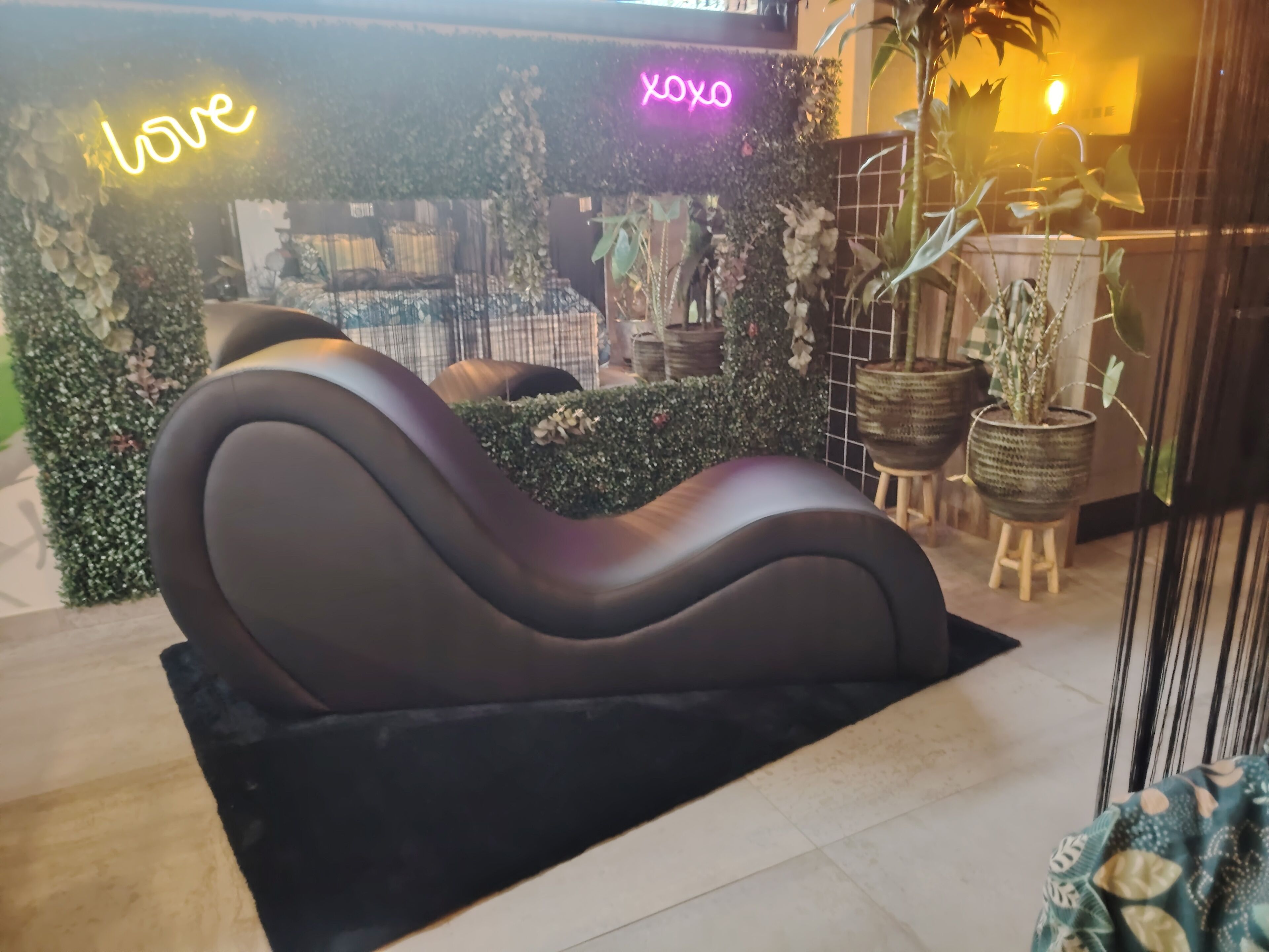 Un espace de détente moderne, doté d’un aménagement de sièges incurvé, entouré d’une végétation luxuriante et de plantes en pot.