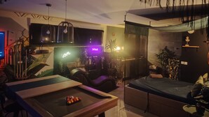 A cozy living room with a pool table, a sofa, and a bar area with a neon sign. - Suites Spa Détente de la lys (La Gorgue)