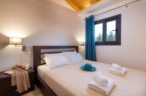 Een slaapkamer met een bed, nachtkastjes, een raam met gordijnen en uitzicht op bomen.