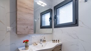 A bathroom with a marble wall, a wooden vanity, a sink with a mirror, and a window. - Apartment Deluxe Suite with Sea View B close to Beach with Shared Pool & Wi-Fi (?e???da)