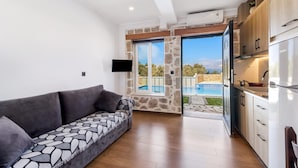 Una sala de estar moderna con un sofá, un televisor y una cocina con refrigerador.
