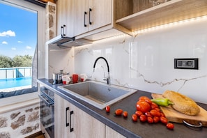 Une cuisine moderne dotée d’un grand évier, de meubles en bois et offrant une vue sur une piscine.