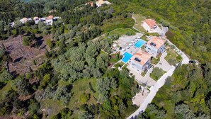 An aerial view of a coastal property with multiple buildings, a swimming pool, and a road leading to the sea. - Apartment "Superior Apartment A" close to the Beach with Shared Pool & Wi-Fi (?e???da)