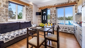 A modern kitchen with stone walls, a dining area with a table and chairs, and a sofa. - Apartment "Superior Apartment A" close to the Beach with Shared Pool & Wi-Fi (?e???da)